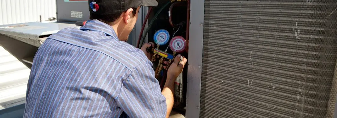 HVAC technician servicing a condenser unit in Cedar Lake